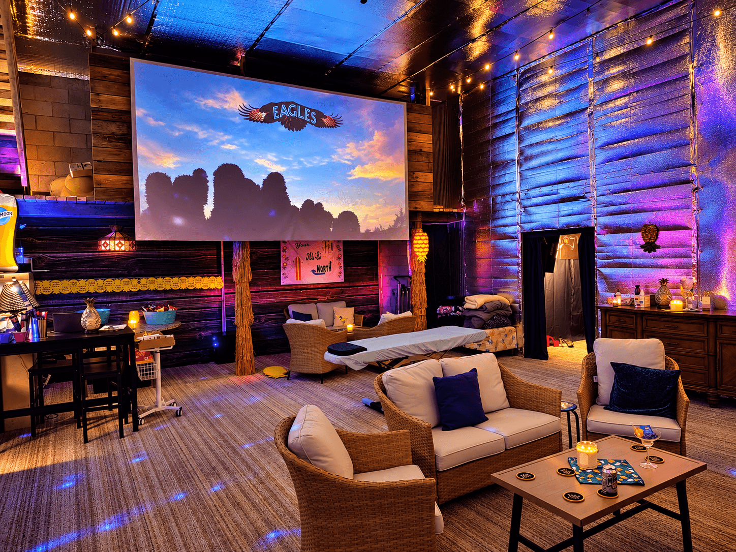 Main room of the Your Ali-Bi Clubhouse with lounge seating, video wall, and evening lighting